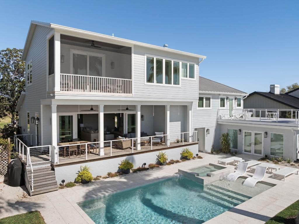 Coastal home exterior with pool, spa, and covered outdoor living area